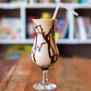 Close-up view of a delicious chocolate milkshake with a straw on a wooden table.