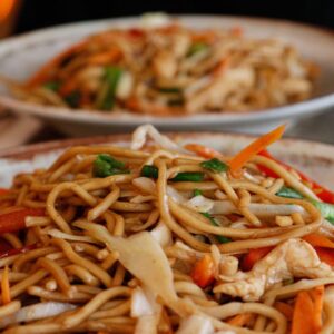 Close-up of flavorful stir-fried noodles with fresh vegetables and chicken.