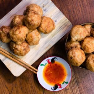 Delicious Indonesian fried snacks served with spicy dipping sauce on a wooden table.