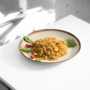 A plate of flavorful fried rice with shrimp and garnishes on a clean white table.