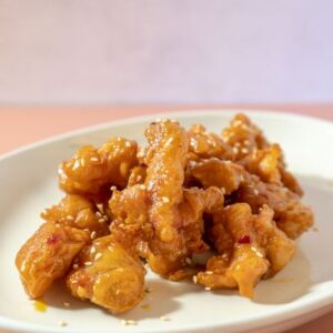 Delicious honey glazed fried chicken served on a white plate, showcasing Indonesian flavors.