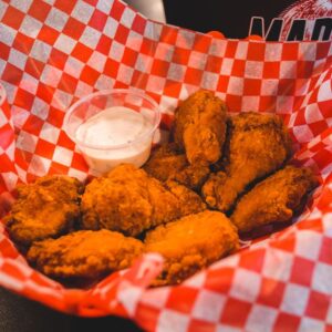 Tasty crispy fried chicken wings served with ranch dipping sauce on a checkered paper.