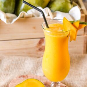 Delicious mango smoothie in a glass garnished with mango slices, ideal for a summer refreshment.
