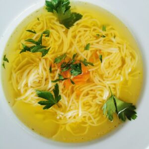 Warm bowl of homemade chicken noodle soup garnished with parsley.